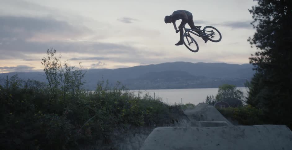 A bicyclist goes over a jump at sunset