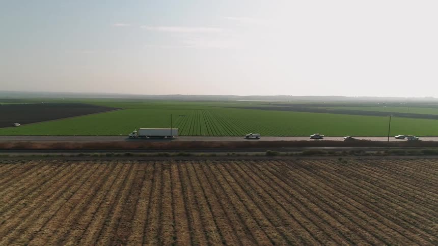 Vehicles travel down a rural farm road