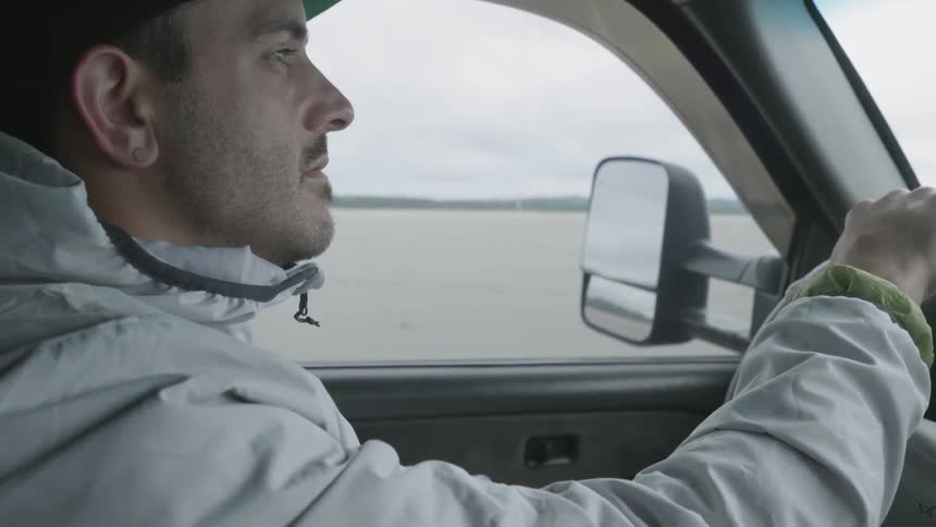 A man drives a truck on white sands