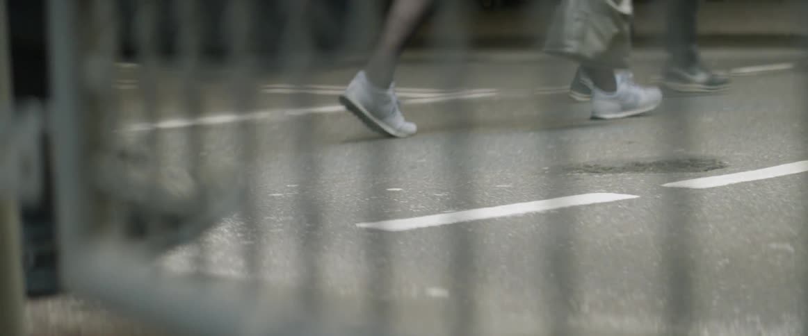 People walk on the street past the fence