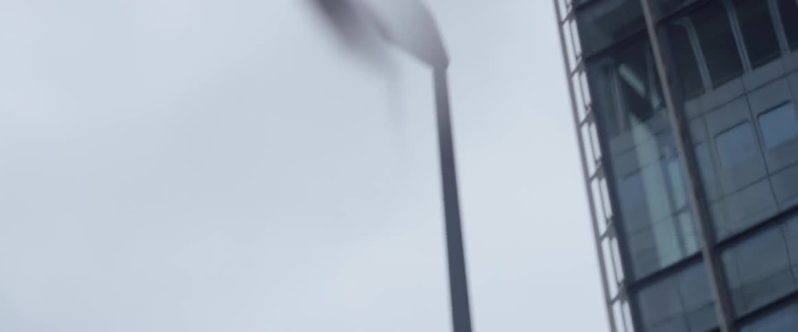 Glass windows in a high rise building are reflecting its environment on a cloudy day