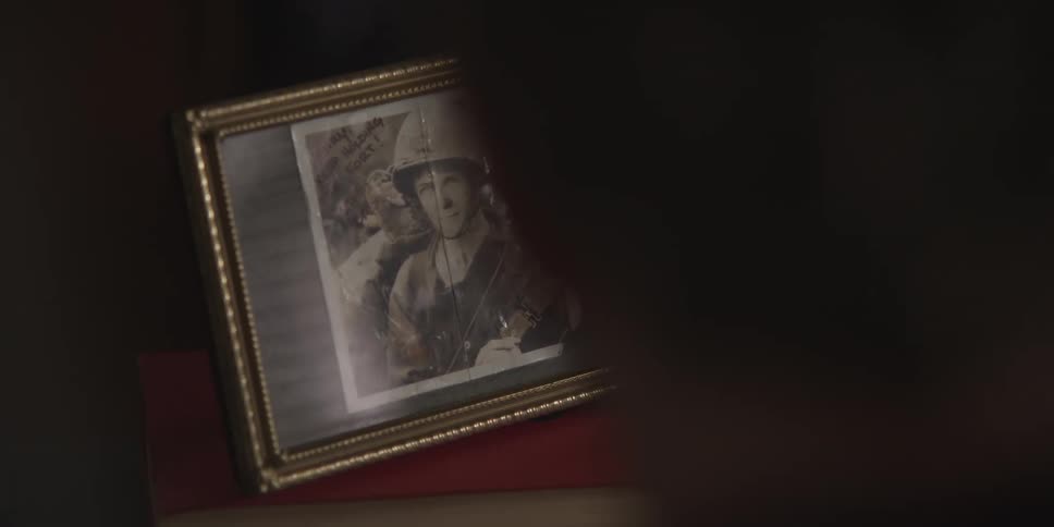 A framed war time photo of a soldier sits on top of a book