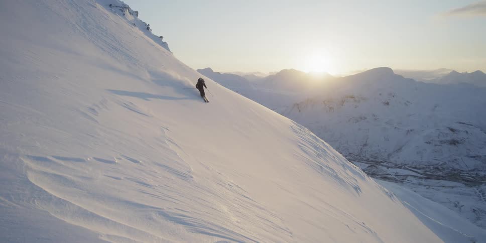 A person skiing down a sunset slope
