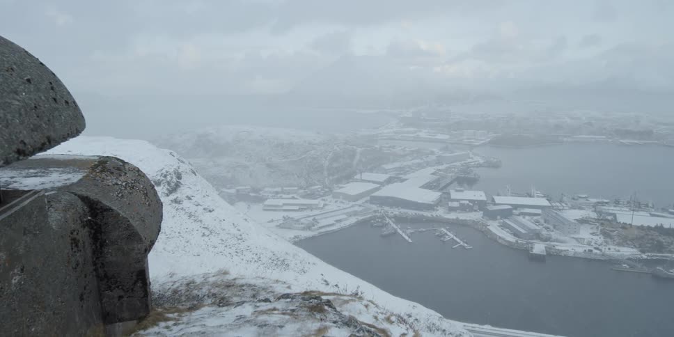 Snow falls on the mountain top above a village