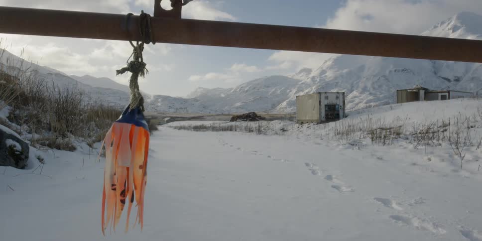 A shredded buoy hands from a rusted gate