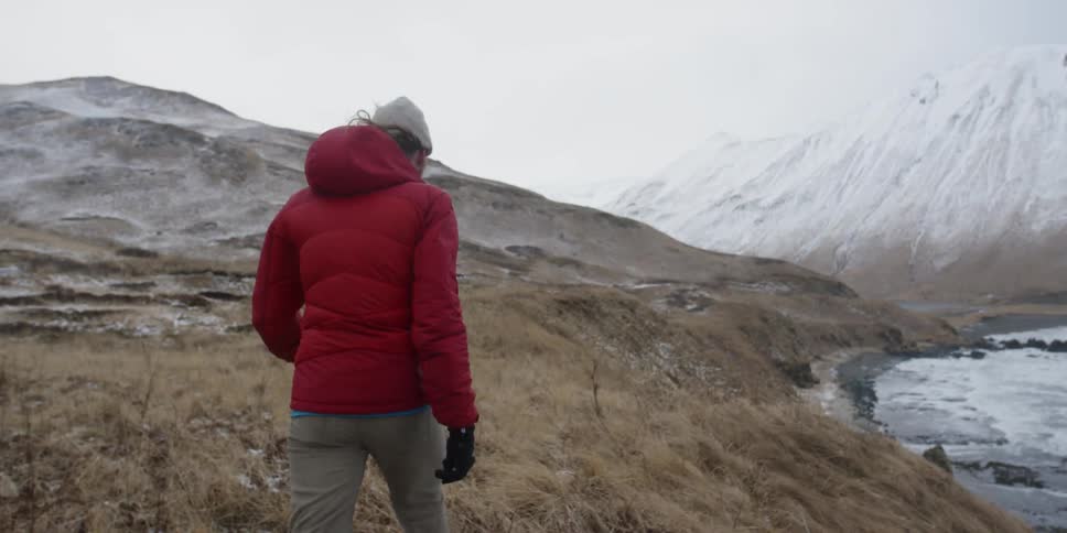 Man hikes next to a mountain lake in winter