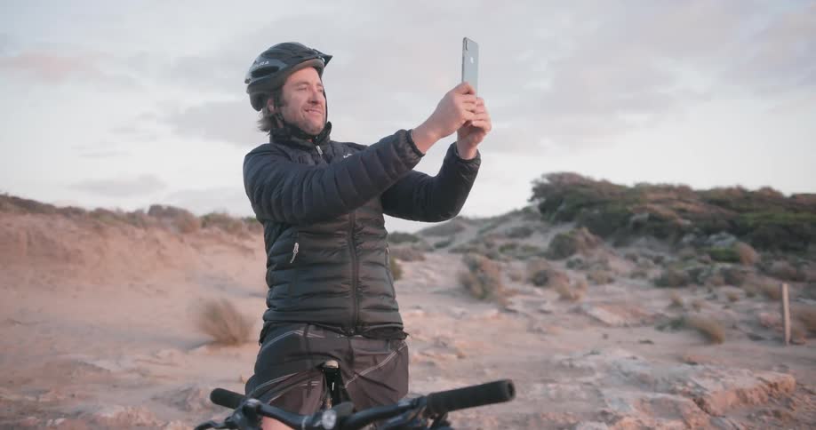 A bicyclist stops to take a photograph at sunset