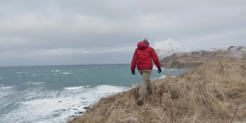 A man is hiking on the hill by the water