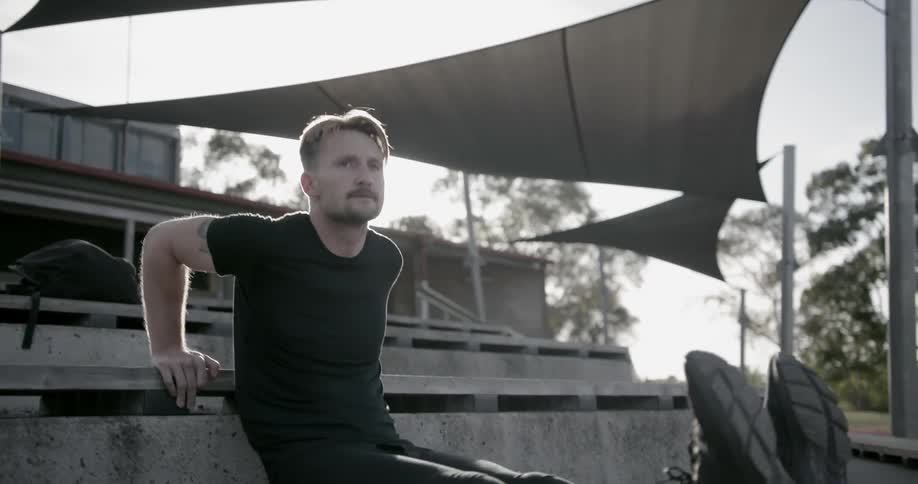 A man does push-ups on outdoor bleachers
