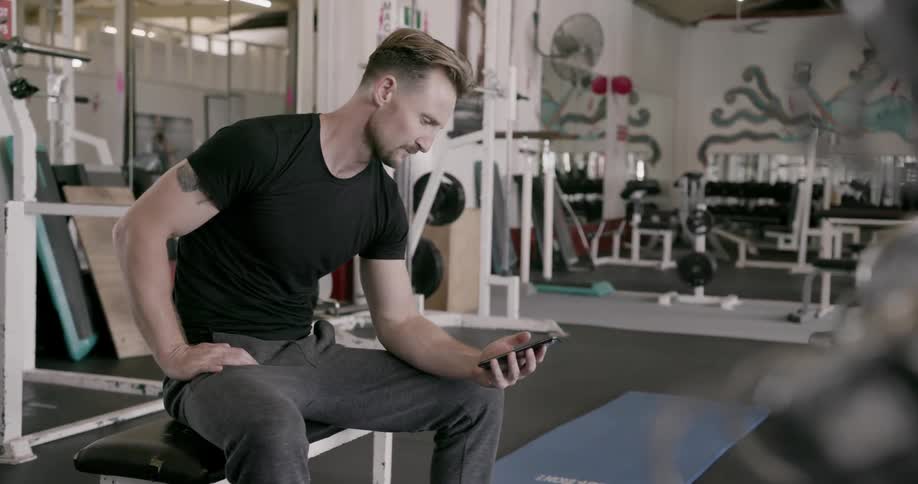A man uses his phone in the gym