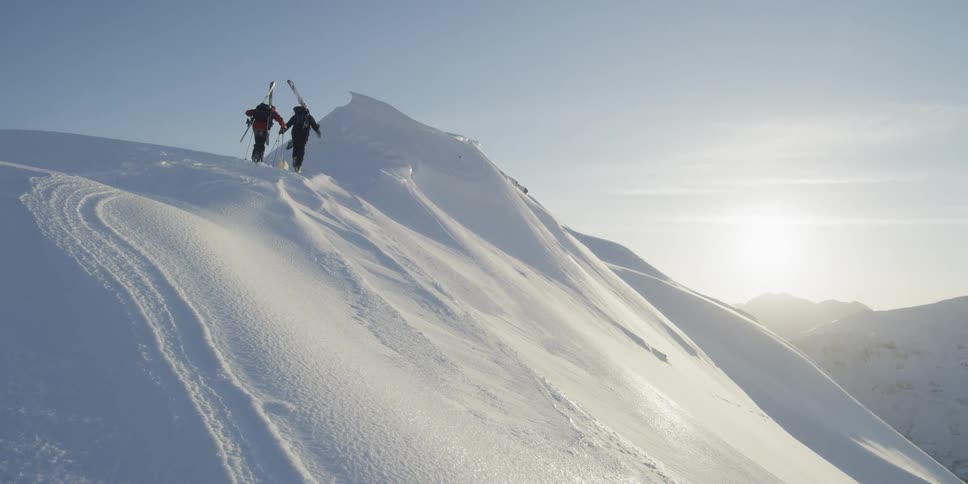 Skiers hike up a snowy mountainside