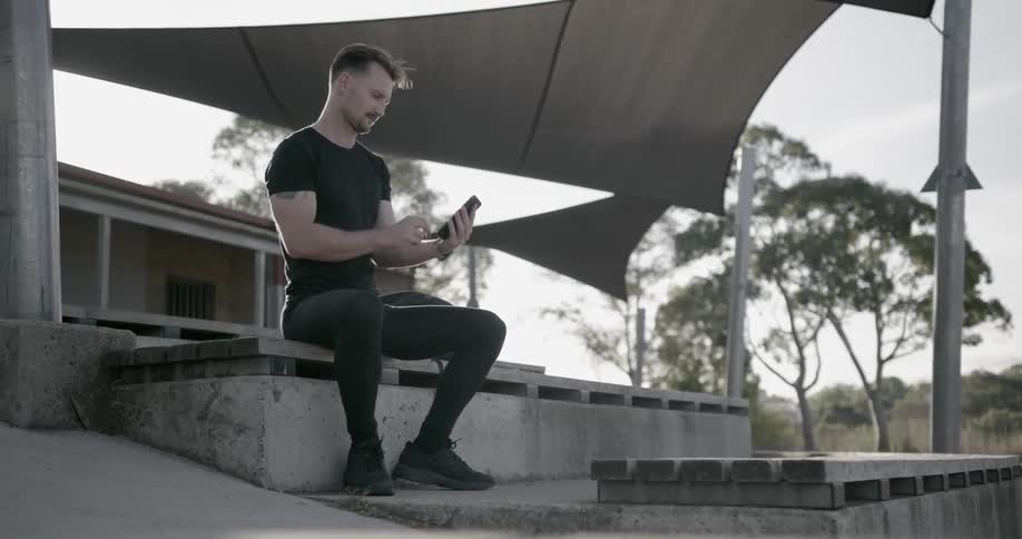 A man uses his phone while sitting on the concrete