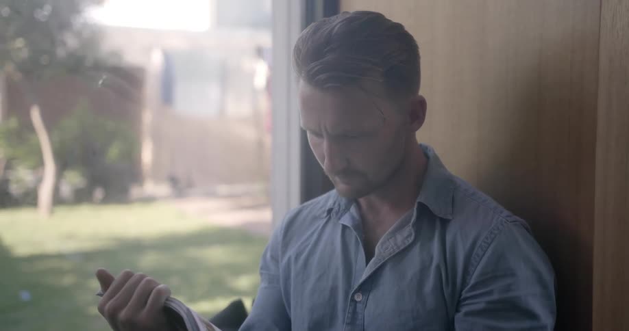 A man sits by the window reading