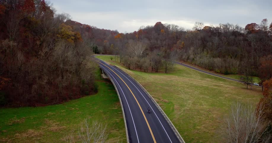 A motorcyclist rides on a rural road