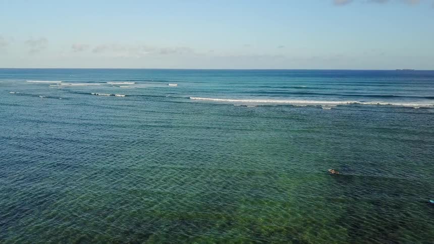 Surfers are paddling out towards waves on a sunny day