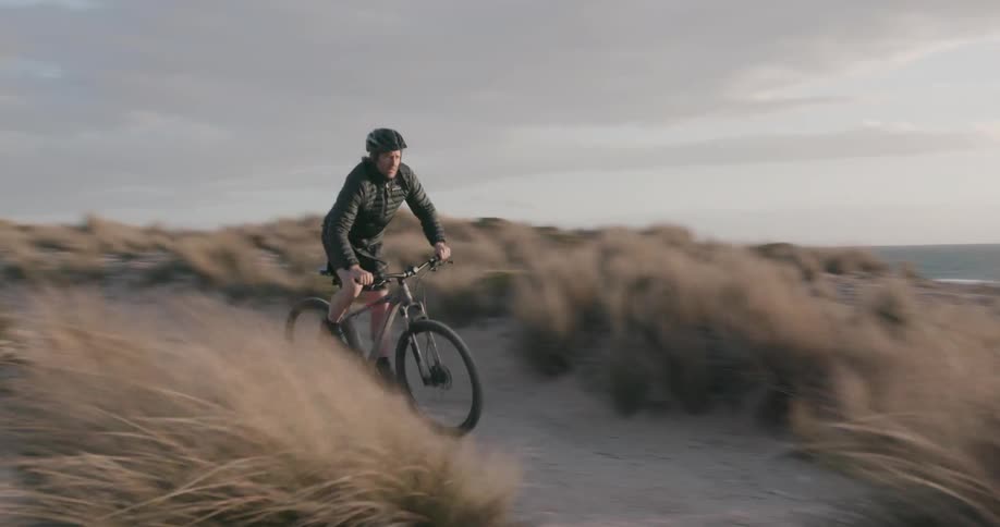 A man rides his mountain bike by the shore