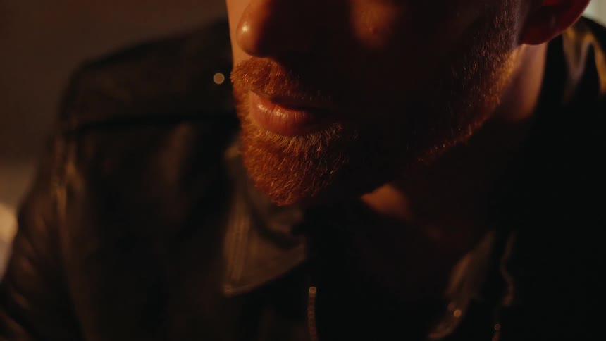 A man looks down blinking in a dark area