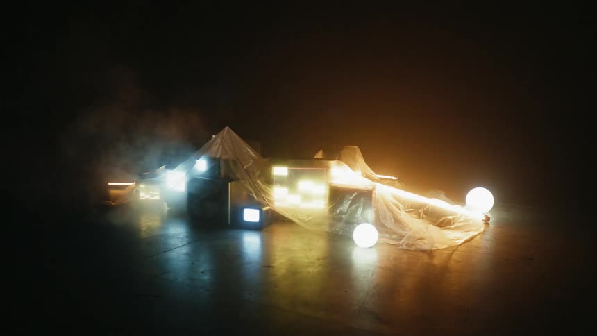 A pattern is flashing on a television sitting under a sheet of plastic with other equipment