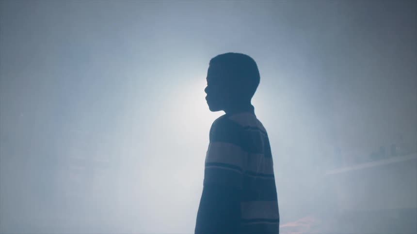 A boy stands in front of a spot light
