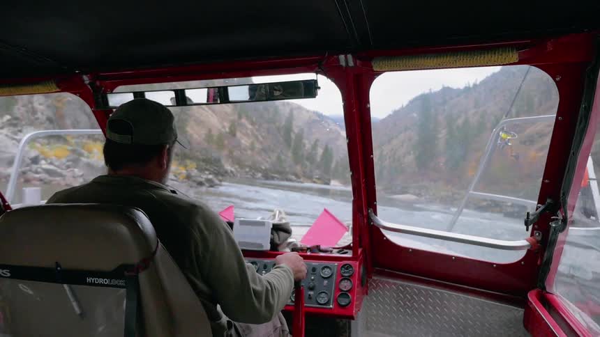 A man is steering a boat in a stream