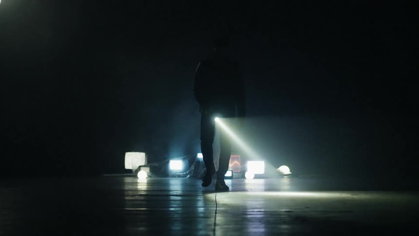 Man shines a flashlight while walking through a dark warehouse