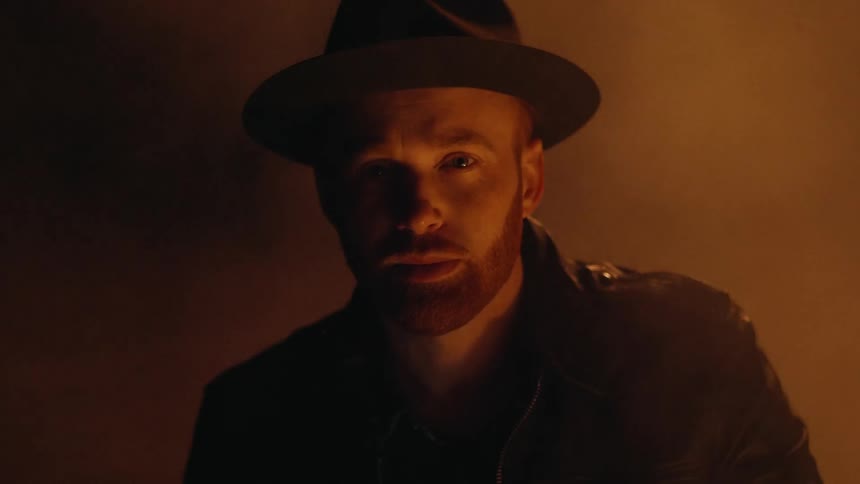 Smoke floats behind a man standing in the dark