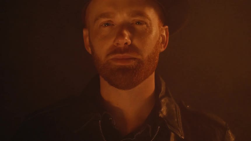 Smoke floats behind a man standing in the dark