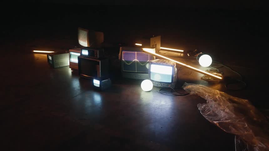 A collection of monitors and televisions sits on the floor in a dark room