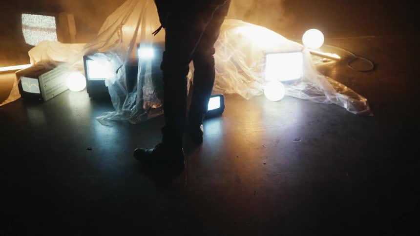 A man removes a plastic sheet from tvs sitting on the floor