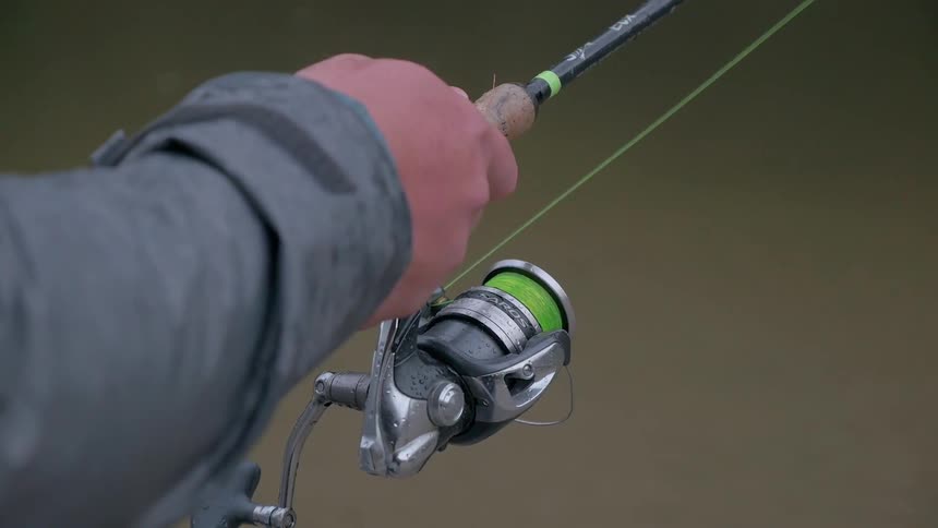 A man holds a fishing pole with a reel