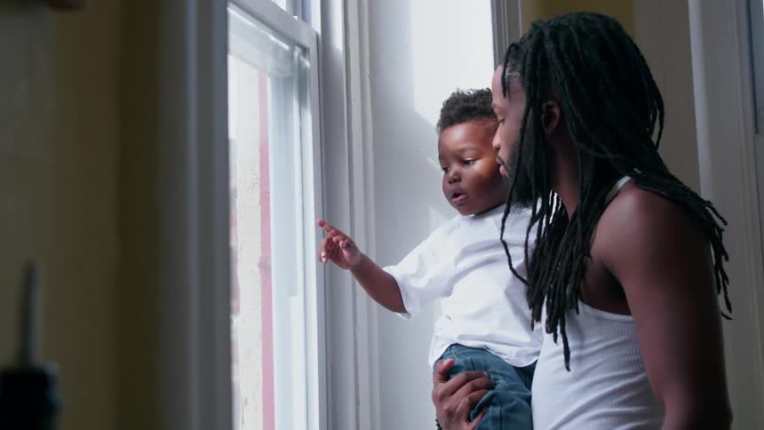 A man holds his child by the window