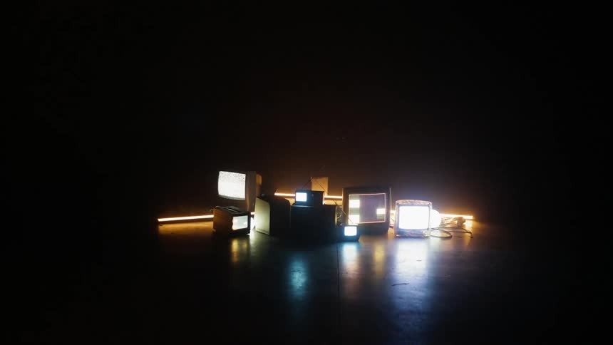 Tvs sit on the floor in a dark room