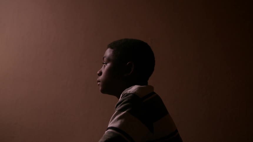 A child sits staring forward blinking