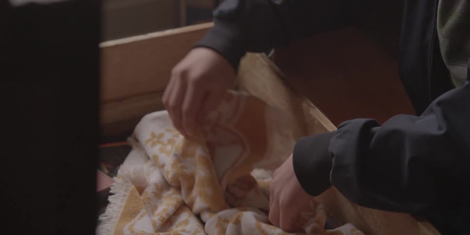 A person opens a chest and looks at an old photograph