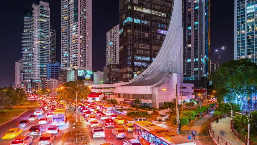 Traffic and pedestrians travel through a city at night