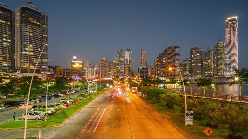 Traffic and pedestrians travel through a city at night