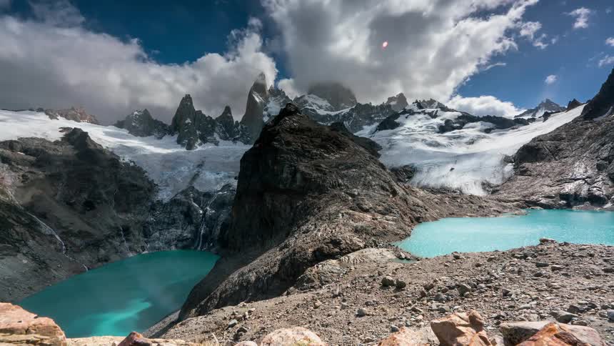 People hike near lakes in a mountain setting during the day