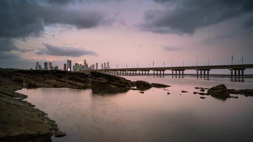 Time-lapse of clouds moving over a bridge area with a large city in the distance