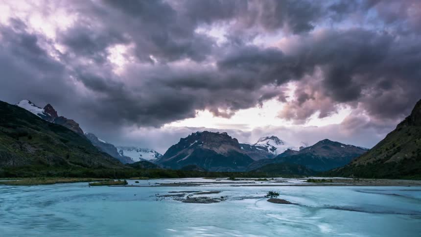 Large dark clouds moving over snowy mountains