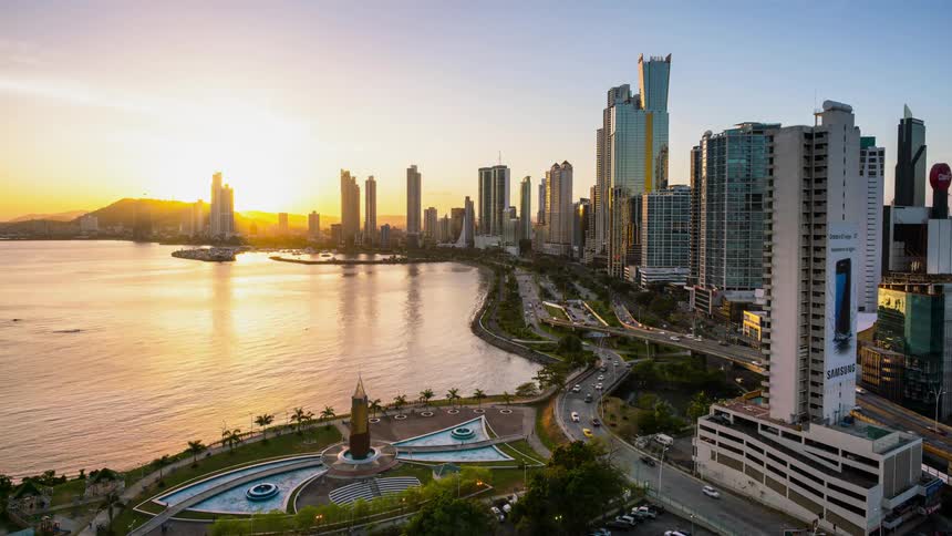Cars travel on a coastal city highway at sunset