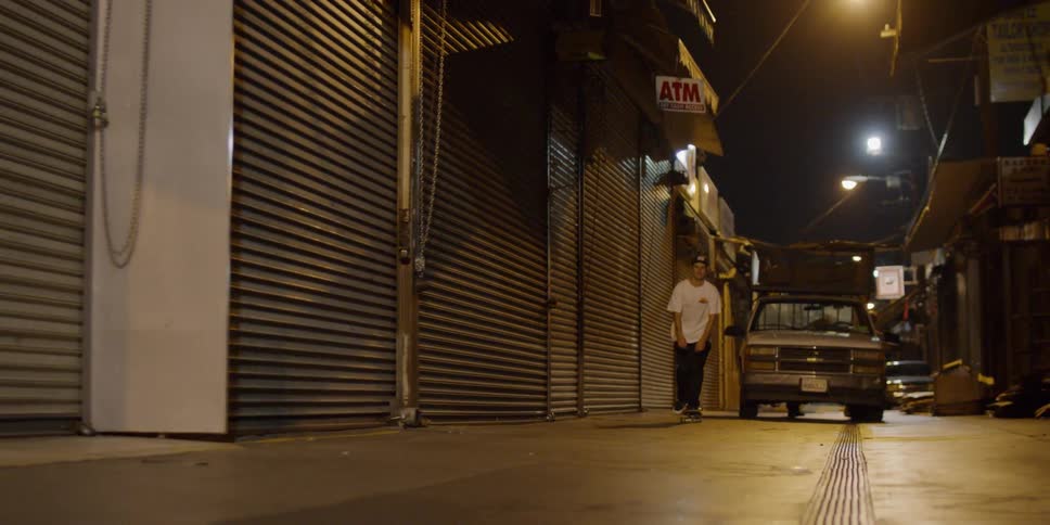 A teenager is riding a skateboard in a city alley at night