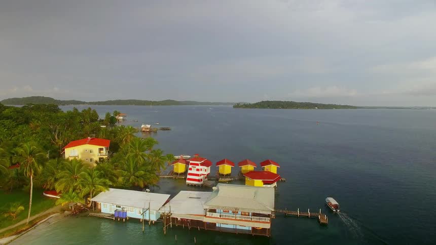 Colorful stilt houses float among palm trees on the ocean shore in Bocas del Toro