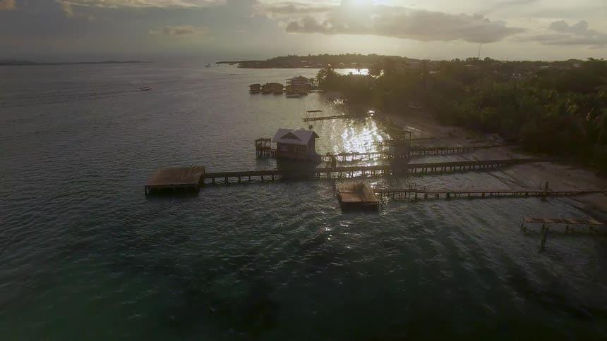 A boat is sailing past the piers of the Bocas del Toro island in Panama at sunset