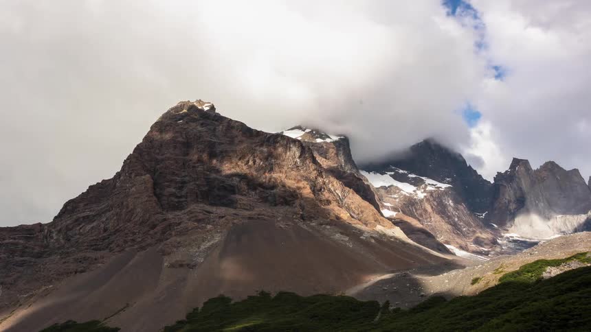 Clouds pass above a snow capped mountain