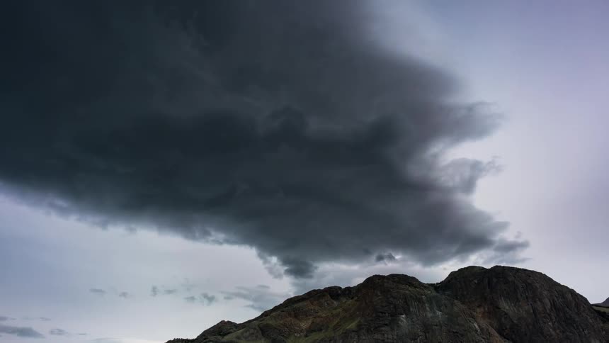 Clouds form and drift over a mountain during the day