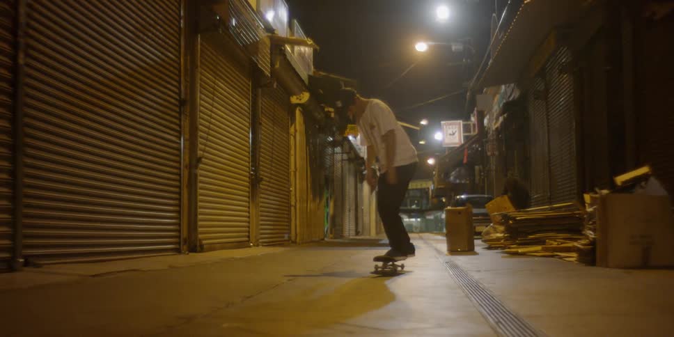 A man rides a skateboard passed closed store fronts