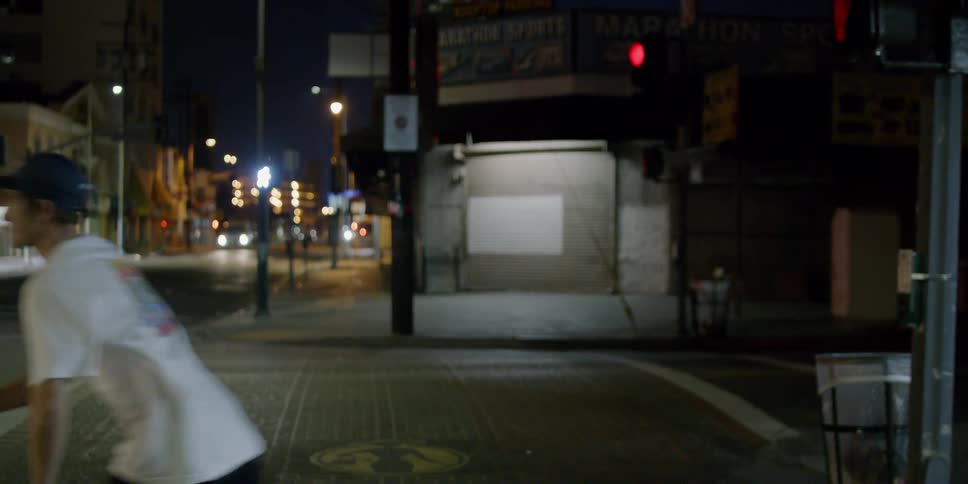 A man rides his skateboard across street