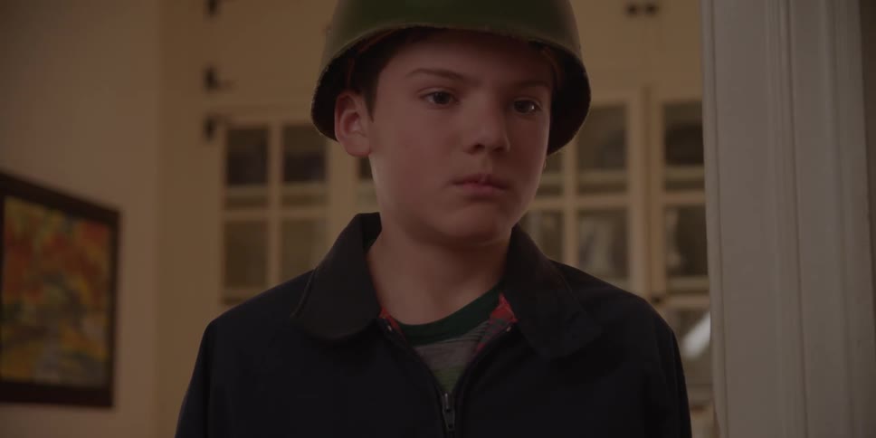 Boy wearing a helmet stands inside a home