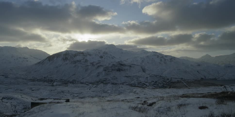 Clouds passing over snowy hills at sunset