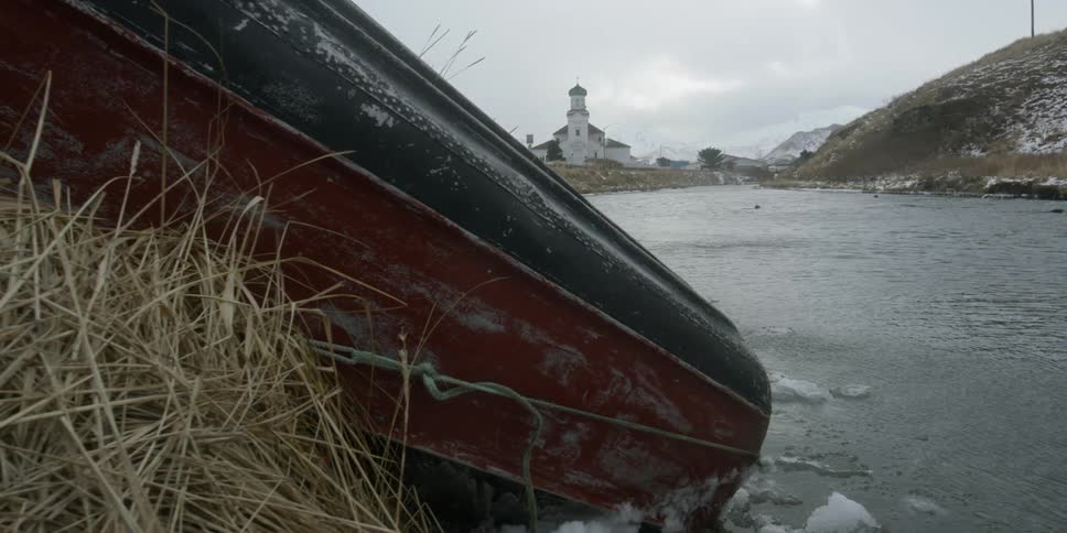 A boat sits overturned along a river